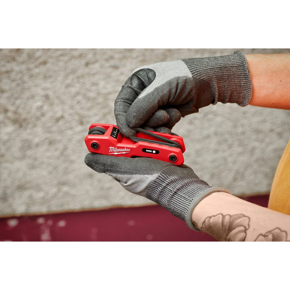 Red folding hex key set with eight metric keys held in gloved hands.