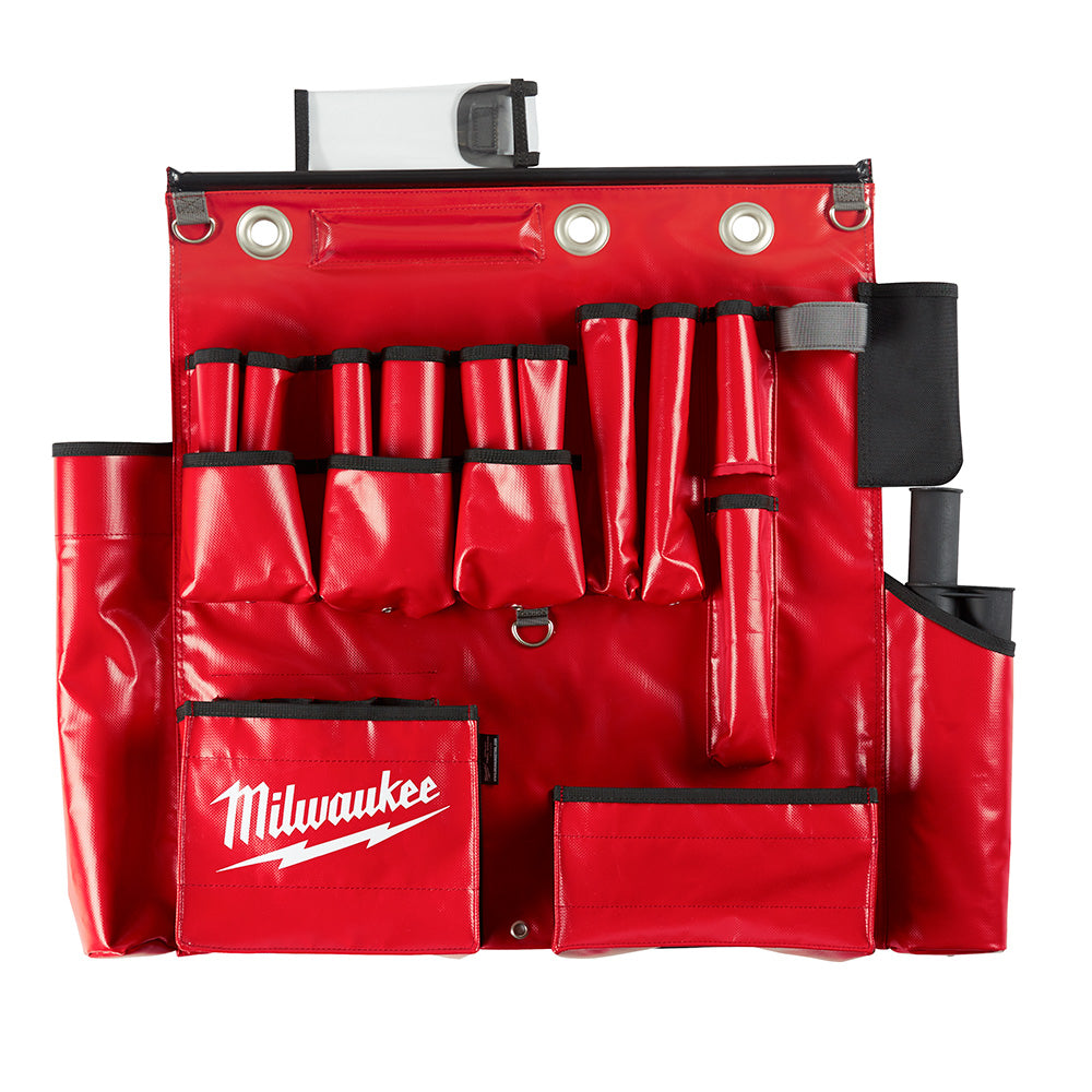 Red tool apron with multiple pockets, metal grommets, black straps, and Milwaukee branding on front pocket.