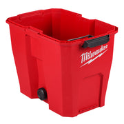 Red plastic vacuum tank with Milwaukee branding, black handle, and drain plug on lower side.