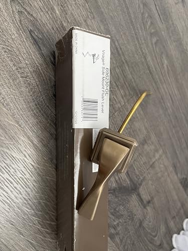 Brizo Virage side mount flush lever in brushed bronze with gold accent handle on wooden surface.