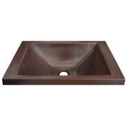 Rectangular hammered copper bathroom sink with curved basin and self-rimming edge in dark brown patina.