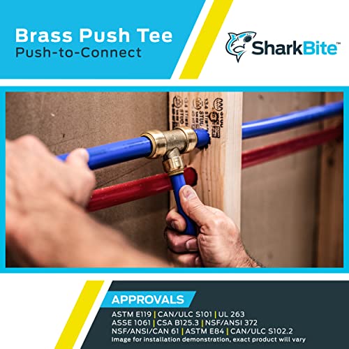 Brass tee fitting with three push-to-connect ports, one blue and one red tubing inserted, mounted on wooden surface.