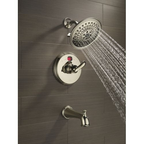 Oil rubbed bronze shower arm with round showerhead and valve trim mounted on gray tile wall.