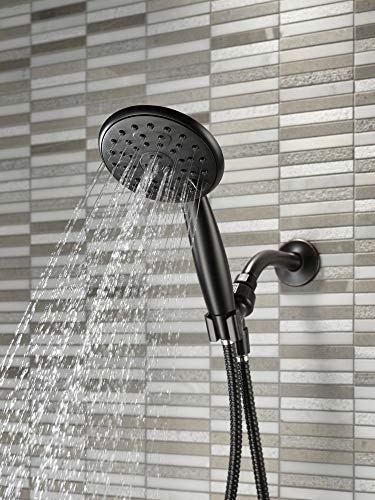 Oil rubbed bronze hand shower with perforated head and braided hose mounted on striped tile wall.