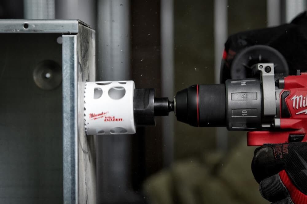 Milwaukee 3" hole saw with bi-metal construction mounted on red drill, drilling into steel angle iron.