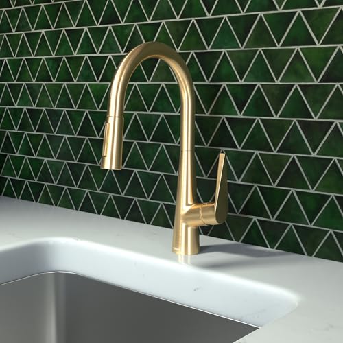 Brushed gold high-arc kitchen faucet with pull-down spray head mounted above stainless steel sink.