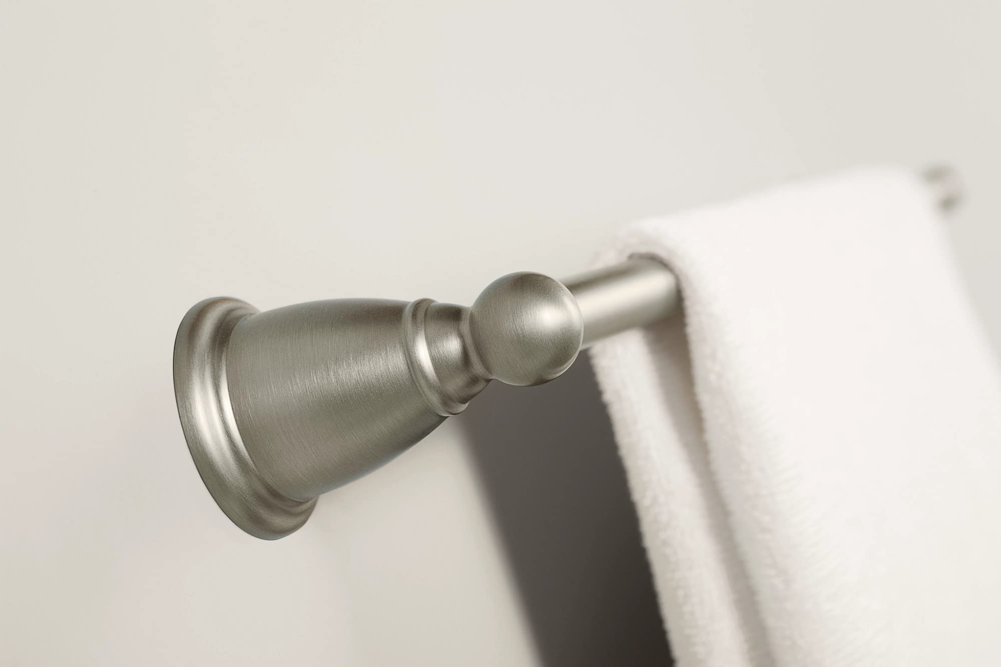 Brushed nickel wall-mounted towel bar with decorative finial and white towel hanging on right side.