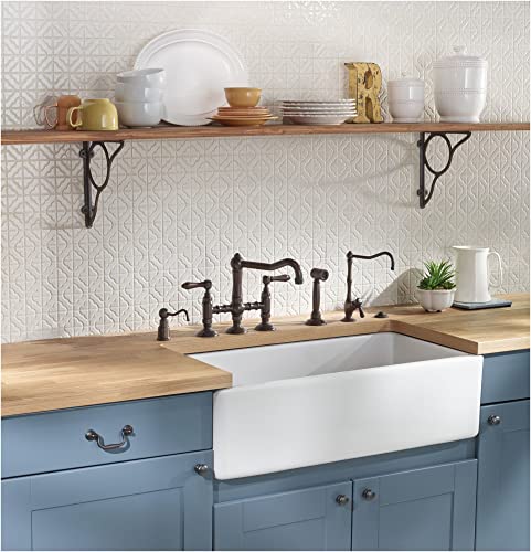 Tuscan brass bridge kitchen faucet with side spray mounted above white apron sink in blue cabinetry with wooden countertop.