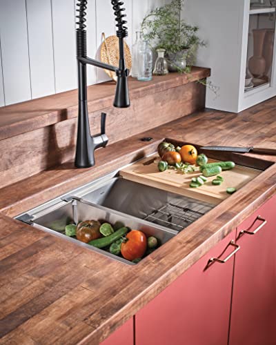Stainless steel undermount sink with black pull-down faucet, wooden cutting board, and metal drying rack installed in wood co