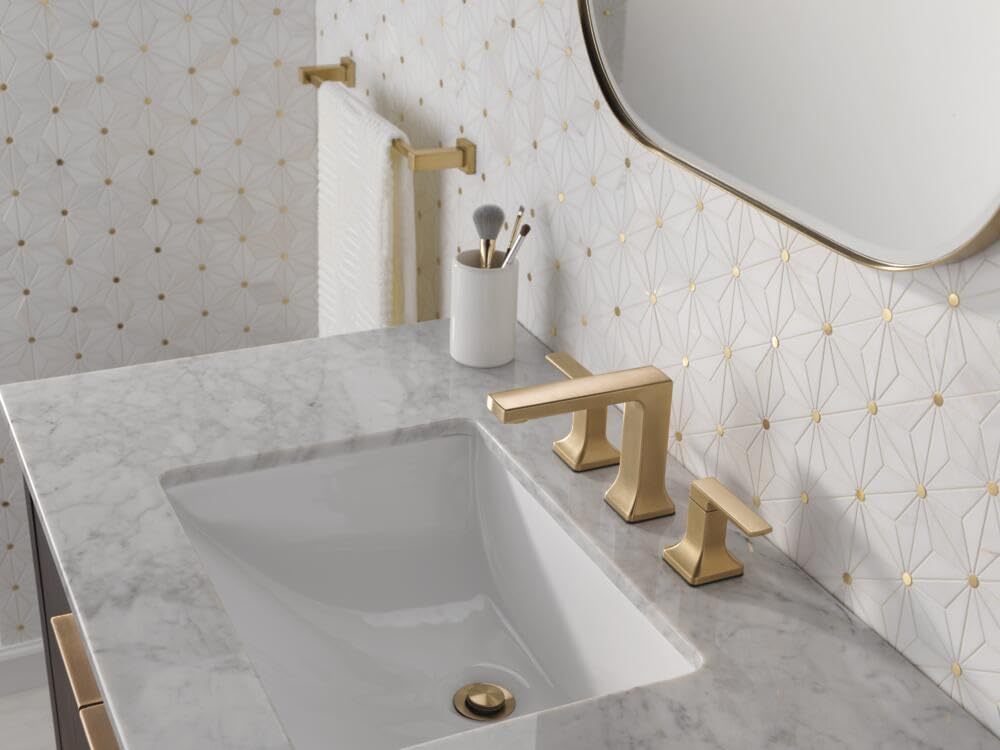 Champagne bronze two-handle widespread faucet installed on marble bathroom sink with rectangular spout and lever handles.