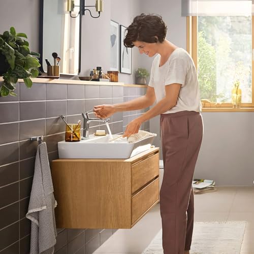 Chrome single-hole bathroom faucet with curved spout installed on white vessel sink in wooden vanity.