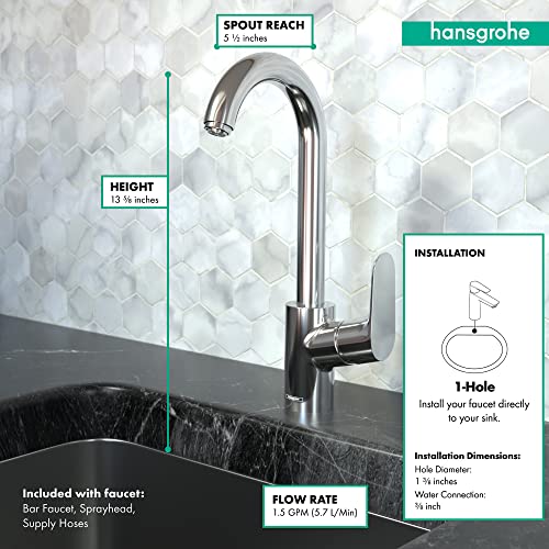 Brushed gold single-handle bar faucet with curved spout mounted on black countertop against white hexagonal tile backsplash.