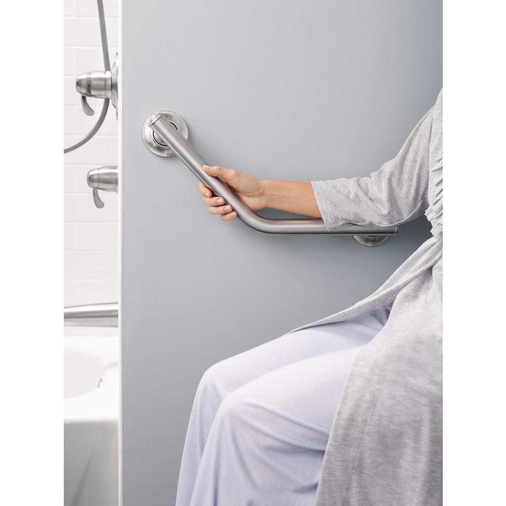 Chrome angled grab bar mounted on gray bathroom wall with person's hand gripping it.