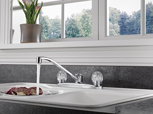 Chrome two-handle kitchen faucet with curved spout over white sink basin.