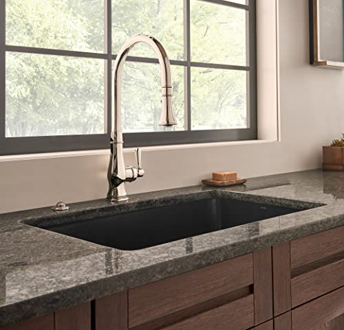 Satin black rectangular fireclay undermount kitchen sink installed in granite countertop with chrome pull-down faucet.