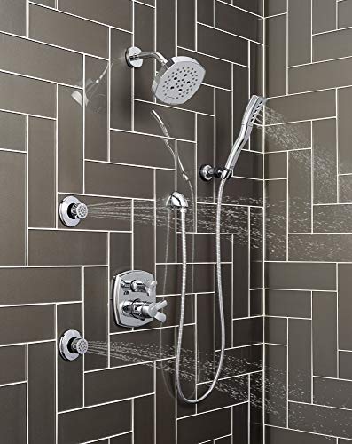 Chrome shower system with overhead rainfall showerhead, handheld spray wand, and multiple body jets mounted on dark tile wall