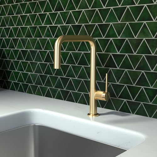 Brushed gold kitchen faucet with U-shaped spout mounted above stainless steel sink against green tile backsplash.