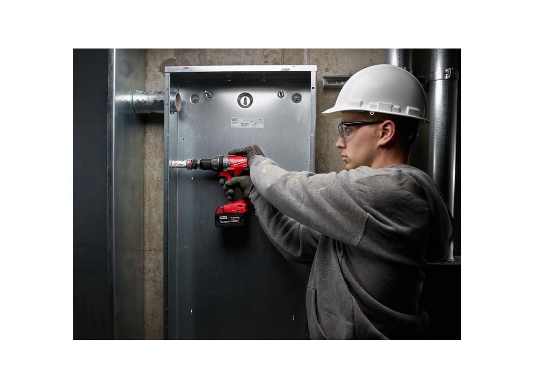 Worker using red cordless drill with hole saw attachment on metal electrical box.