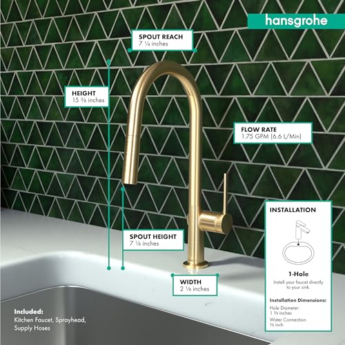Brushed gold arc kitchen faucet with pull-down spray head mounted on white sink against green tile backsplash.