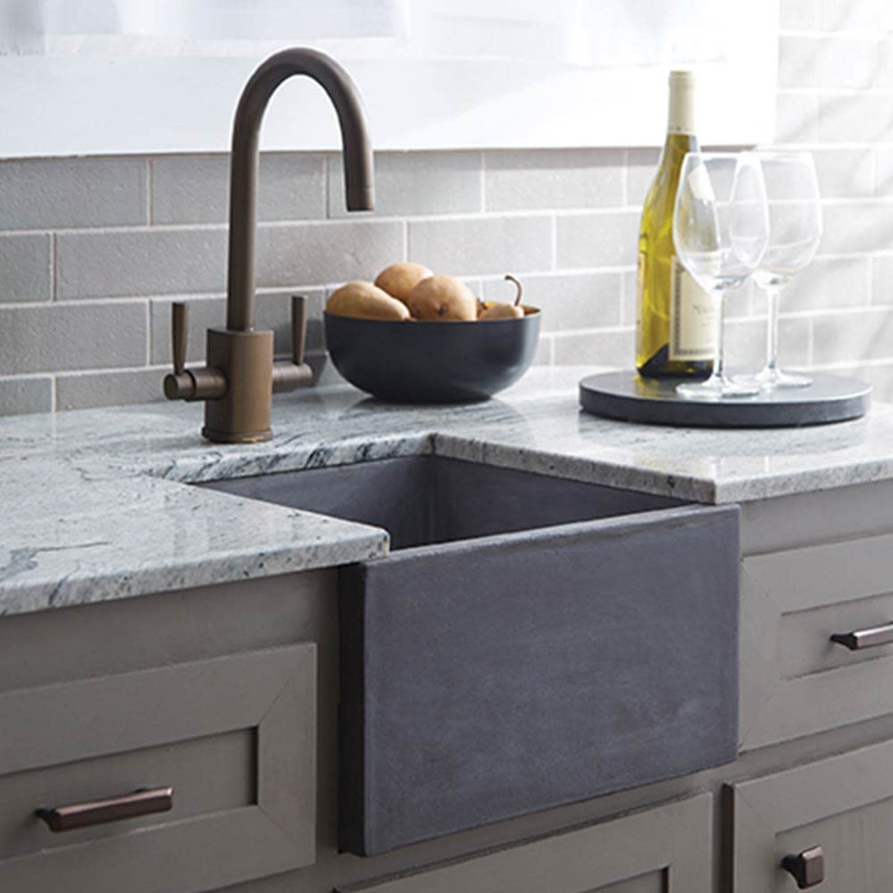 Slate farmhouse bar sink with arched bronze faucet, marble countertop, white subway tile backsplash, and styling props.