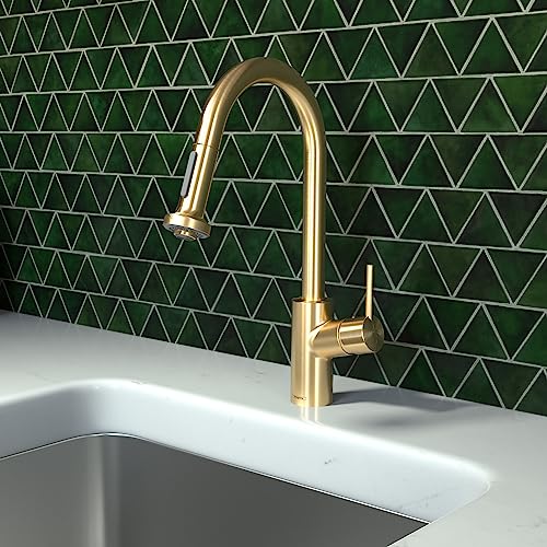 Brushed gold kitchen faucet with curved pull-down spout mounted above white countertop and stainless steel sink.