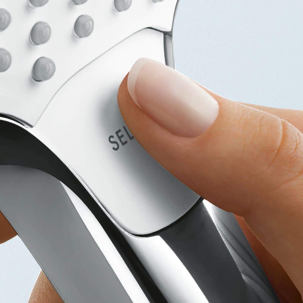 Finger pressing a control button on a white and black brushed nickel shower head with multiple jet nozzles visible.