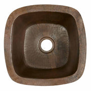 Small square hammered copper sink with rounded corners and center drain hole, viewed from above.