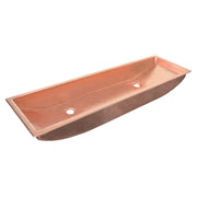Polished copper trough sink with two faucet holes and curved interior basin.