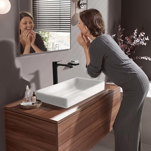 Matte black single-hole faucet mounted on white rectangular vessel sink atop wooden vanity.