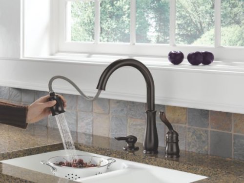 Venetian bronze soap and lotion dispenser with curved spout and pump mechanism mounted on countertop.