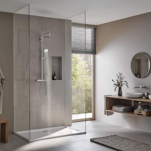 Chrome thermostatic shower system with overhead rainfall showerhead and handheld spray mounted on gray tile wall.