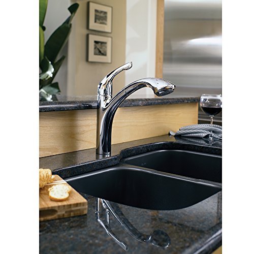 Chrome pull-out kitchen faucet with curved spout installed on black sink in kitchen countertop.