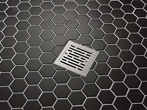 Stainless steel square shower drain with horizontal slats installed in hexagonal tile flooring.