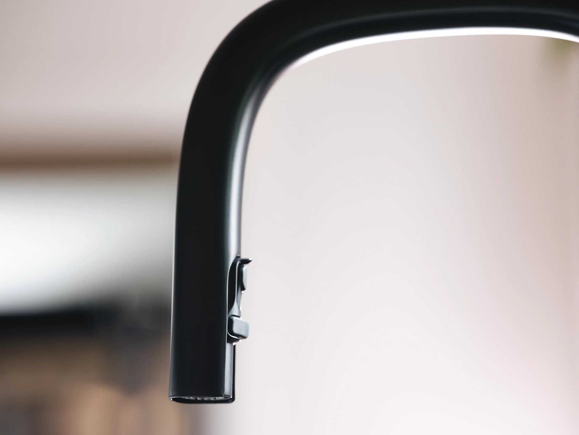 Matte black kitchen faucet with curved spout and pulldown spray head attachment.