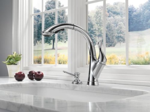 Chrome soap and lotion dispenser with curved spout mounted on white kitchen countertop.