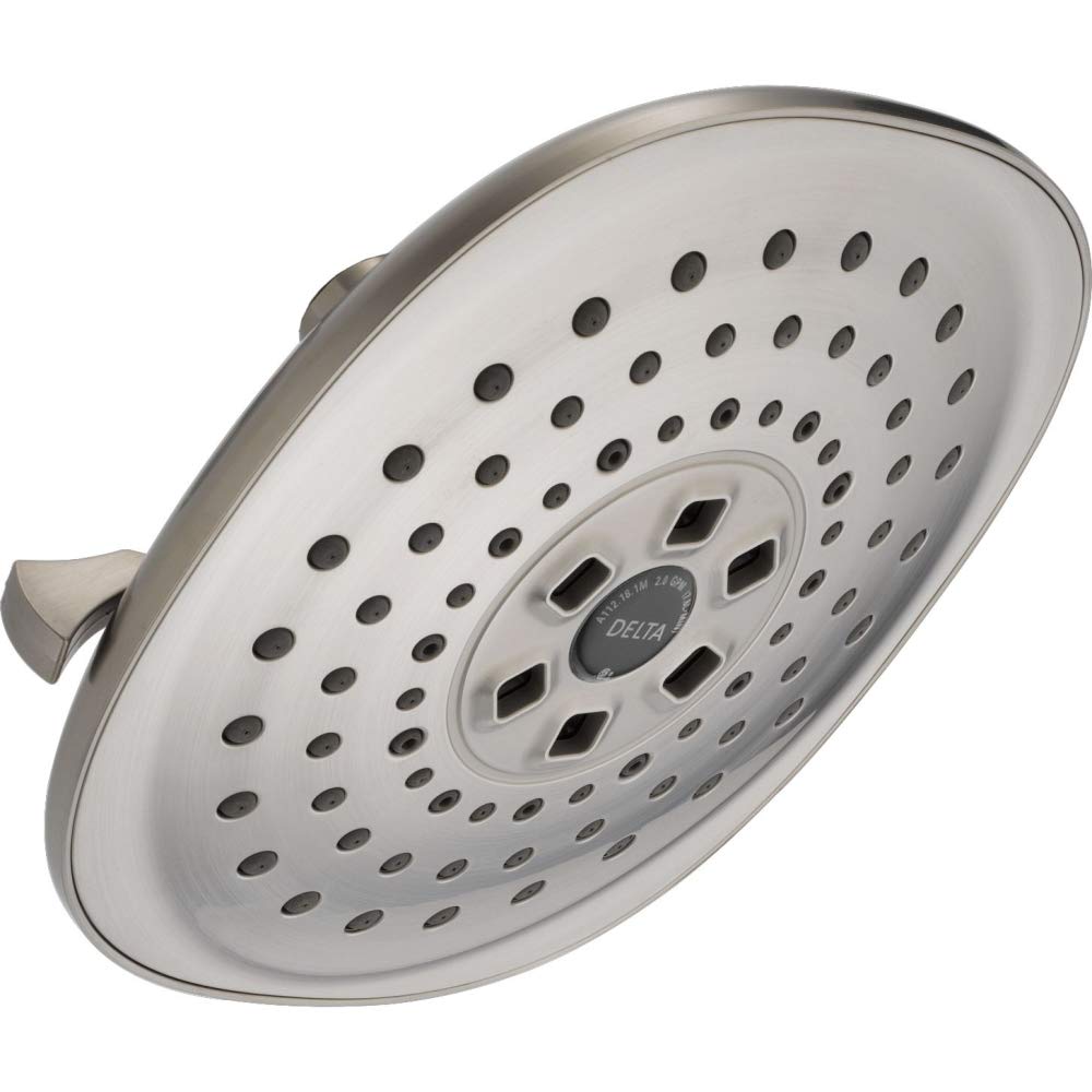Round brushed nickel shower head with multiple spray holes and central control dial mounted on metal arm.