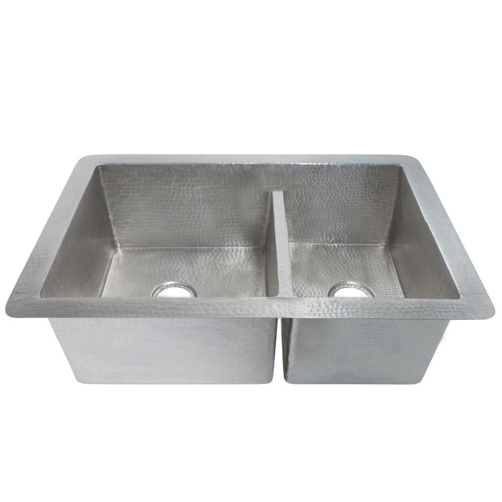 Brushed nickel double-bowl kitchen sink with hammered texture and drain holes visible.