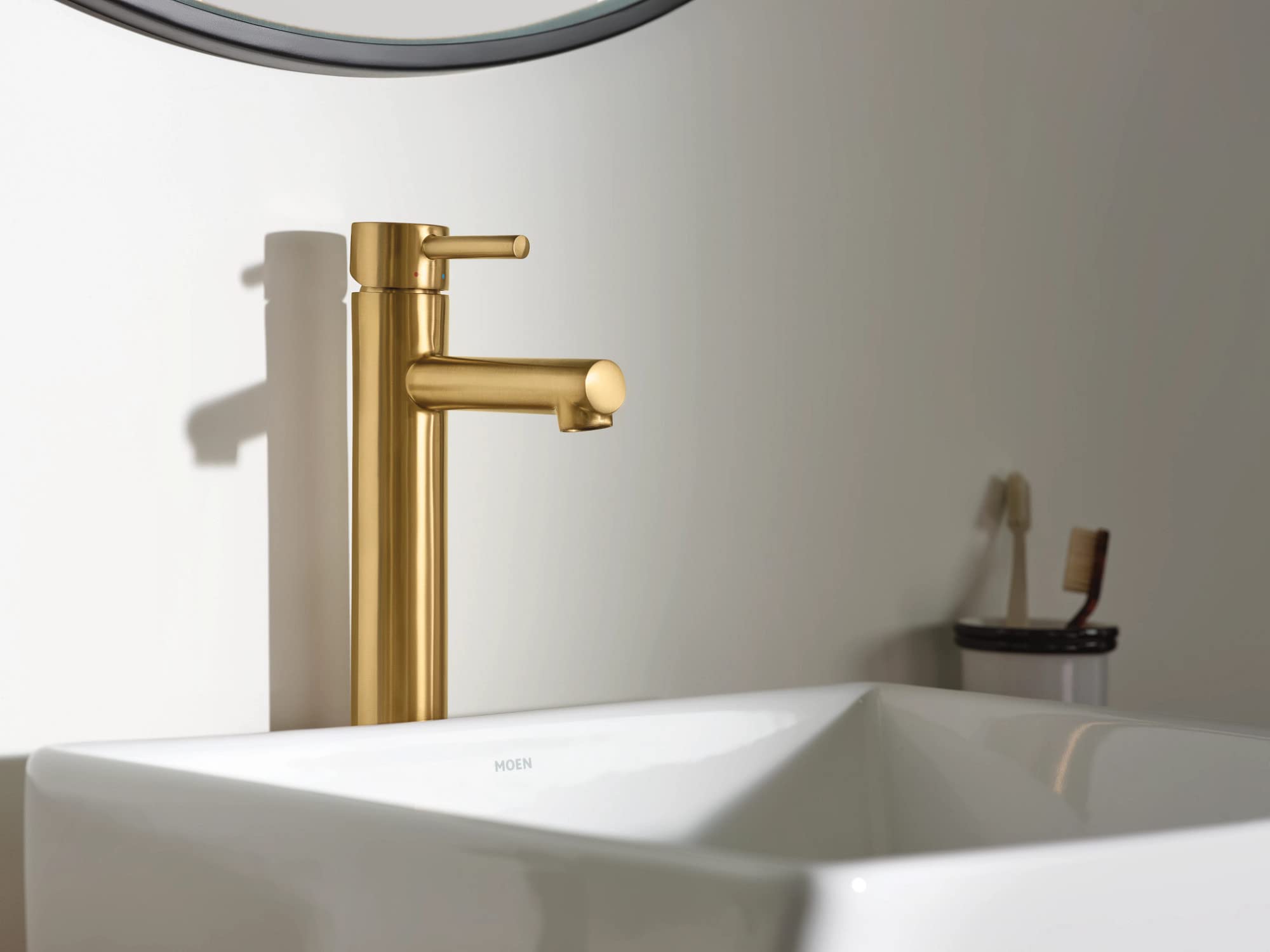 Brushed gold single-handle bathroom faucet with tall spout mounted on white vessel sink.