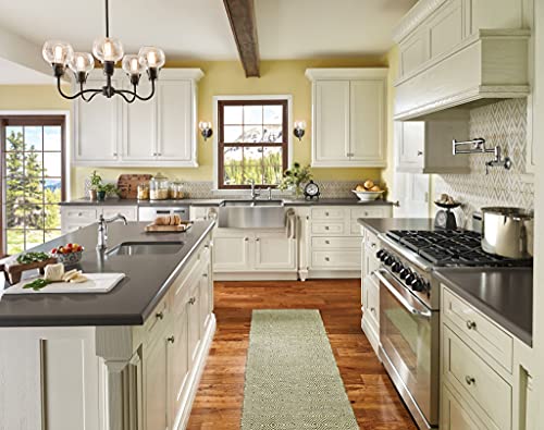 Stainless steel farmhouse sink with apron front and single bowl installed in white kitchen cabinetry.