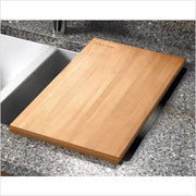 Light wood cutting board resting on sink edge next to white and black sink basin.