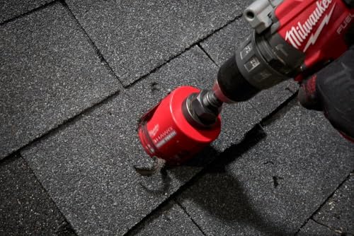 Red Milwaukee 4-1/4 inch hole saw with carbide teeth mounted on drill against dark textured surface.