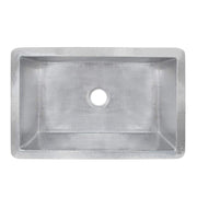 Brushed nickel single-basin kitchen sink with hammered interior and rounded front apron, drain opening centered.