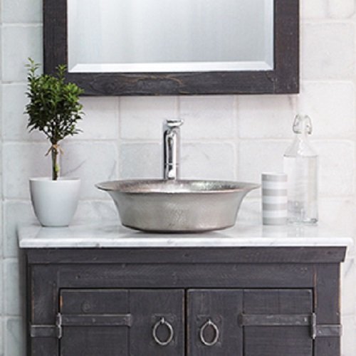 Hammered copper oval vessel sink with textured finish, chrome faucet, displayed on dark vanity with white countertop.