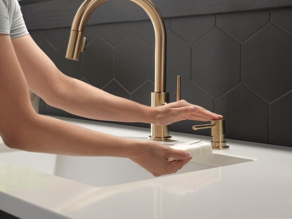 Champagne bronze kitchen faucet with arched spout and matching soap dispenser pump on white countertop.