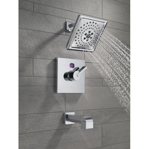 Oil rubbed bronze shower arm mounted on gray tile wall with square showerhead and water stream visible.