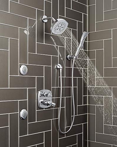 Chrome shower system with integrated diverter, rainfall showerhead, handheld sprayer, and body jets mounted on dark subway ti