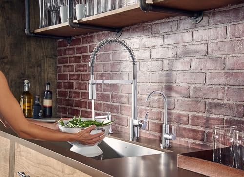Chrome touchless kitchen faucet with high arc spout and pull-down sprayer head at sink.