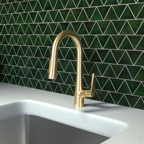Brushed gold kitchen faucet with curved pull-down spout mounted above a stainless steel sink against green tile backsplash.