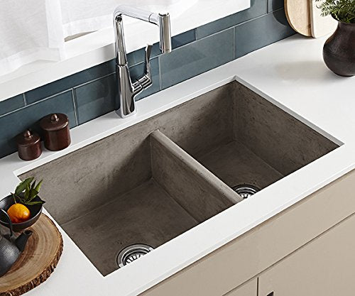 Ash-colored concrete double bowl farmhouse sink with chrome pull-down faucet installed in white countertop.