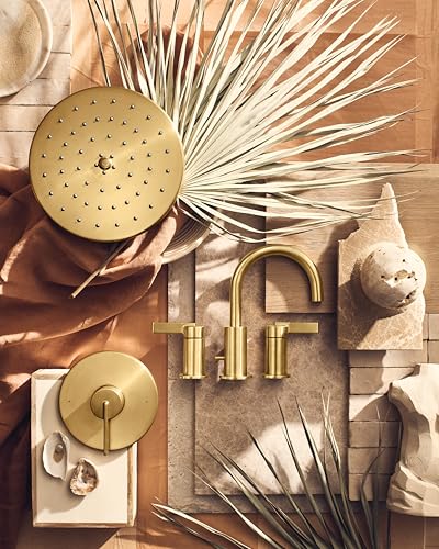 Brushed gold two-handle high-arc bathroom faucet with matching showerhead and valve trim displayed with decorative accessorie
